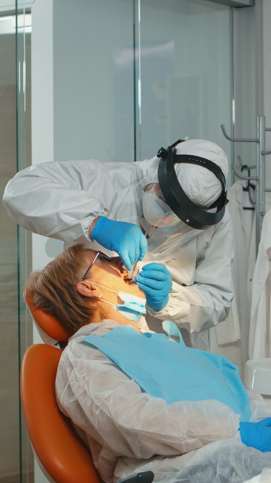 Doctor with protective mask doing hygienic cleaning of teeth